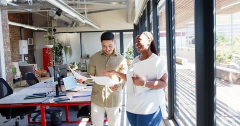 Diverse colleagues walking cheerfully in bright modern office
