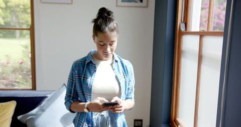 Teenage Girl Engaging with Smartphone in Sunlit Living Room