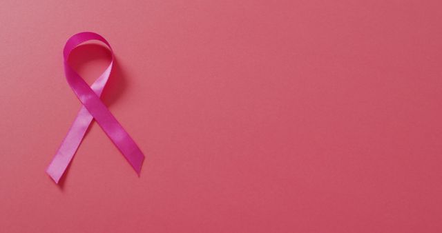 Image of pink breast cancer ribbon on dark pink background. medical awareness support campaign symbol for breast cancer.