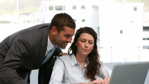 Businessman Assisting Colleague with Work in Modern Office Setting