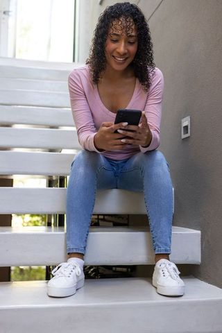 Smiling Young Woman Engaged on Smartphone