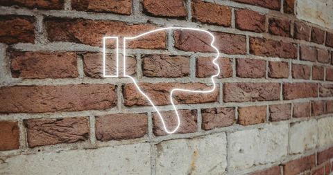 Neon dislike symbol on brick wall background