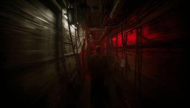 Walking down narrow industrial tunnel with bundled cables and dramatic red lighting