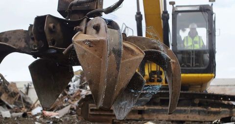 Rusted Grapple Claw in Dynamic Salvage Yard Environment