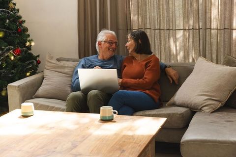 Senior Couple Enjoying Time Together by Christmas Tree with Laptop