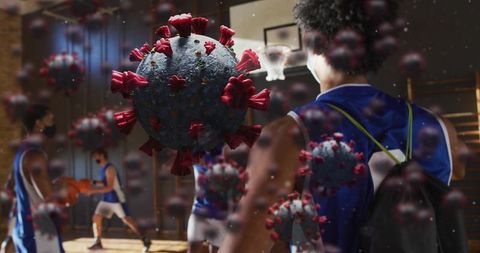 Giant coronavirus particle looming over masked basketball players practicing in indoor court