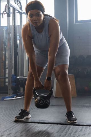 African american woman performing kettlebell hinge with 5kg weight in gym