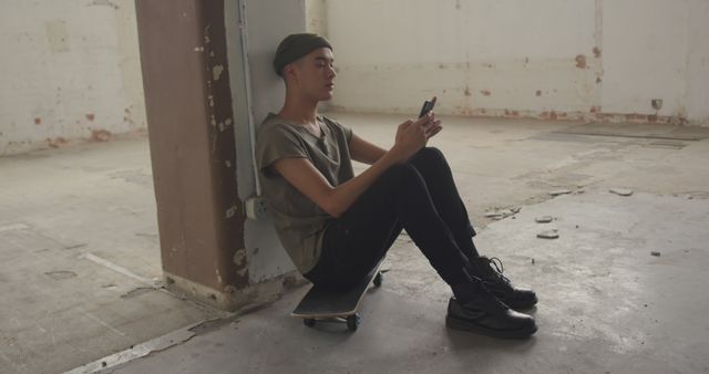 Young Man Sitting Against Pillar Using Smartphone in Abandoned Building - Download Free Stock Images Pikwizard.com