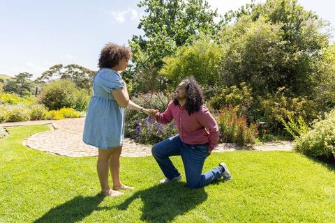 Diverse Couple Proposing on Garden Lawn Under Sunny Sky