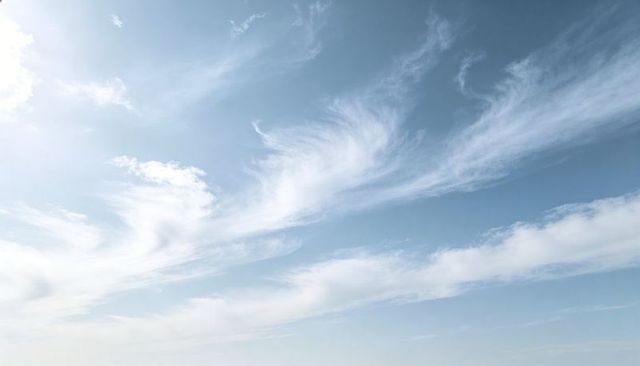 Pale blue sky with wispy cirrus clouds drifting across vast serene high-altitude expanse
