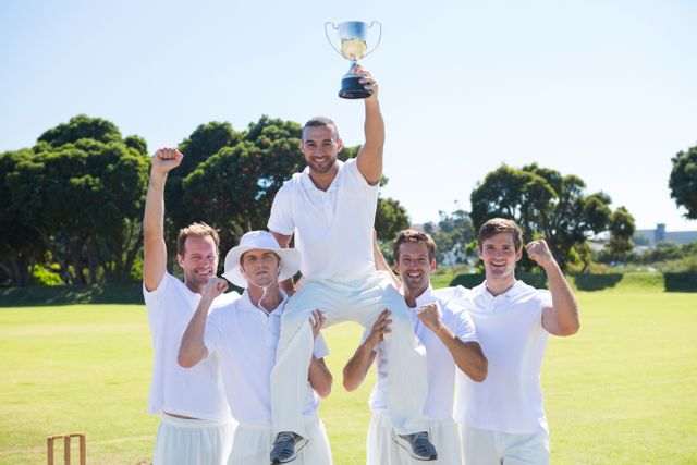 Happy cricket team with throphy standing on field against clear sky