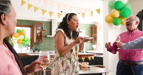 Senior Woman Blows Out Candle with Friends at Birthday Celebration