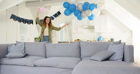 Couple decorating kitchen for birthday party with balloons