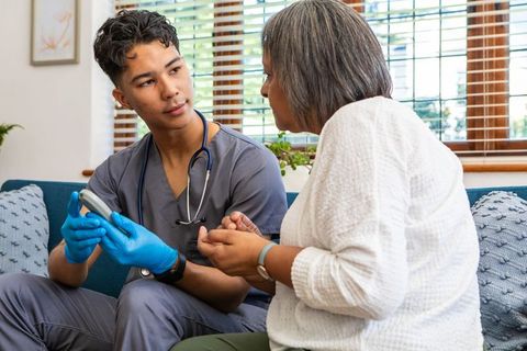Medical Worker Checking Senior Woman's Glucose Levels at Home