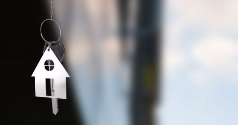 House-shaped keychain over blurred background represents homeownership