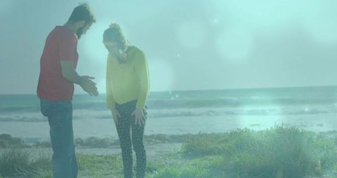 Couple discussing on coastal dune with red shirt man and yellow sweater woman