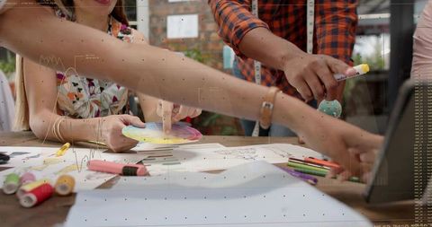 Creative team collaborating over color wheel and sketches arranging layouts on wooden table