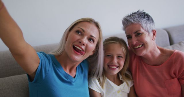 Caucasian grandmother, mother and daughter smiling while taking a selfie with smartphone at home. family, togetherness and happiness concept