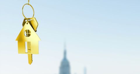 Golden House Keychain with Urban Cityscape Background