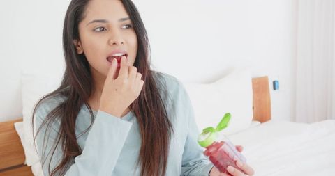 Woman in loungewear taking supplement at home