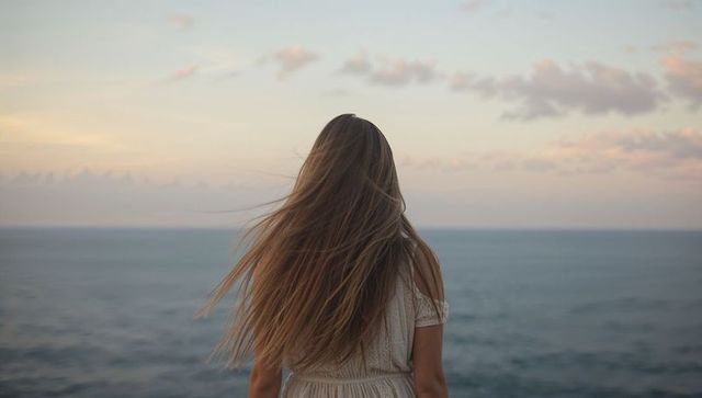 Woman in White Dress Gazing at Serene Ocean Horizon