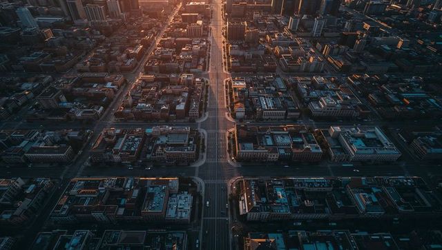 Sunlit central boulevard cutting through symmetrical urban grid at golden hour aerial view