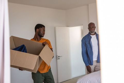 Father and Son Unpacking in New Home with Cardboard Box