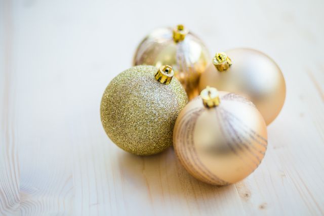 Golden Christmas baubles placed on a light wooden background, perfect for holiday decor inspiration, festive mood promotion, and seasonal greeting cards.