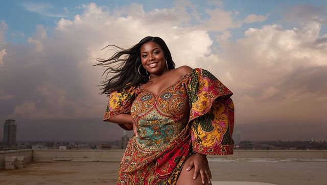 Confident Woman in Vibrant Patterned Dress Expressing Joy on Urban Rooftop
