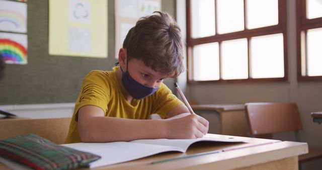 Young Student Wearing Mask in Classroom Writing in Notebook - Download Free Stock Images Pikwizard.com