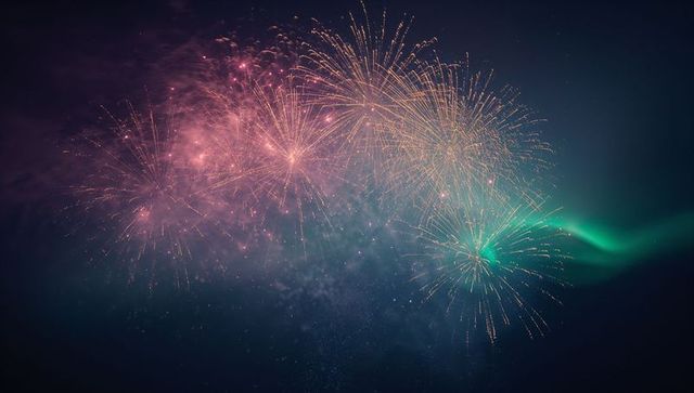 Pink, Gold and Teal Fireworks Bursting Across Night Sky with Aurora-Like Green Streaks