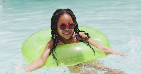 Happy girl enjoying pool time with green inflatable ring
