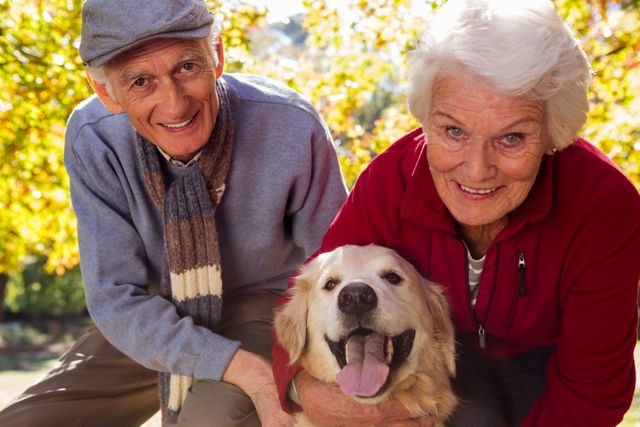 Elderly couple enjoying a sunny day in the park with their golden retriever. Ideal for use in advertisements promoting senior living, pet companionship, outdoor activities, and healthy lifestyles for retirees.
