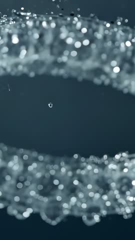 Macro vertical footage of droplets falling from upper strand into center gap, sparkling bokeh