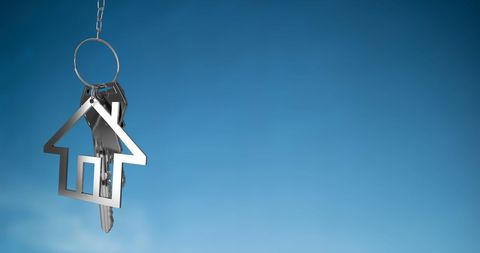 Silver house key on blue background symbolizing real estate