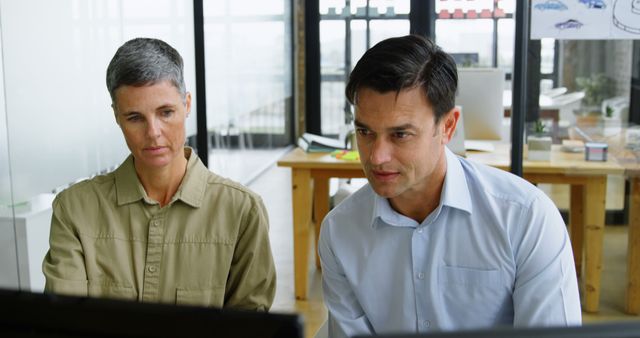 Two professionals intently analyze data on a computer in a contemporary office. - Download Free Stock Photos Pikwizard.com
