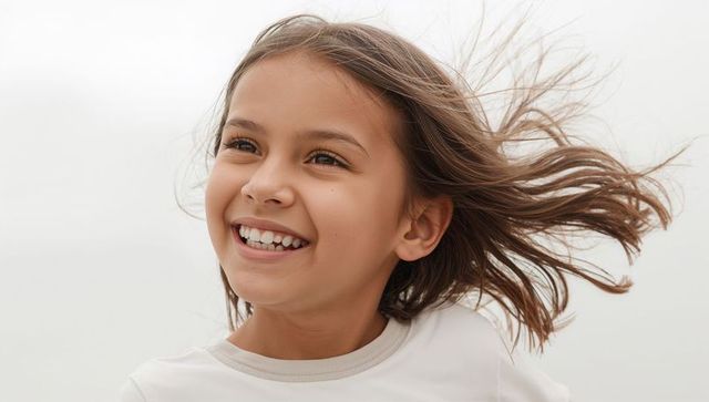Smiling windblown girl looking left wearing white crewneck shirt cheerful youth portrait