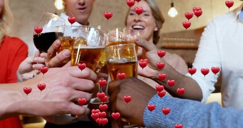 Friends toasting beer and wine in rustic bar with heart balloons celebrating night out