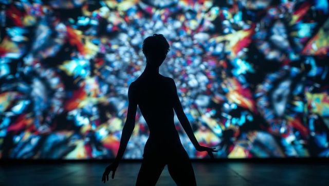 Silhouette of dancer amid multicolored projection display