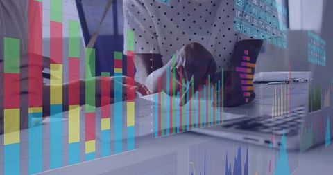 Business team analyzing multicolored data charts and printed reports at desk with laptop
