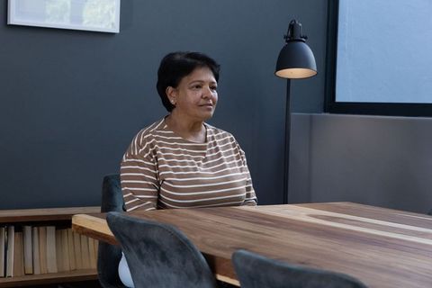 Senior woman reflecting at modern wooden table in home office
