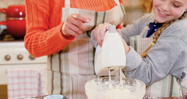 Parent and child mixing baking batter in a kitchen. Both wearing striped aprons, engaging in a fun activity that strengthens family bonds. Ideal for advertising family-friendly products, cooking classes, and kitchen appliances.