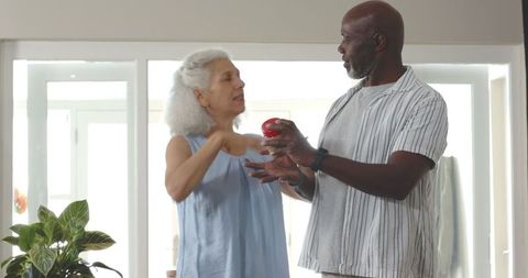 Senior couple sharing fresh bell pepper in modern kitchen
