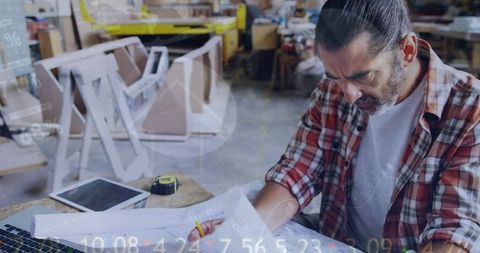 Craftsman planning woodworking project in workshop with instruments