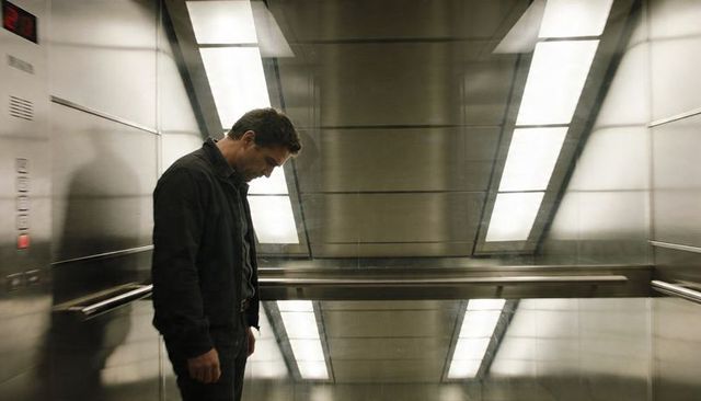 Solitary man standing in mirrored elevator with reflective walls and moody lighting