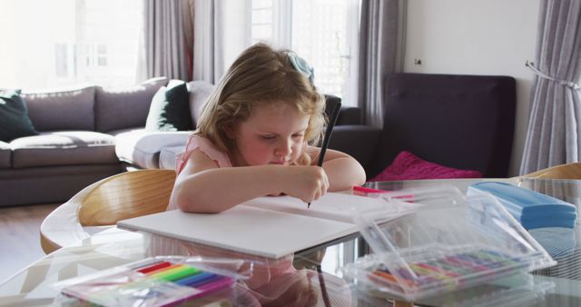 Girl deeply engaged in drawing with colored markers in bright and cozy living room. Ideal for illustrating childhood creativity, indoor activities, educational content, and home environments. Perfect for art education resources, lifestyle blogs, or parenting articles.