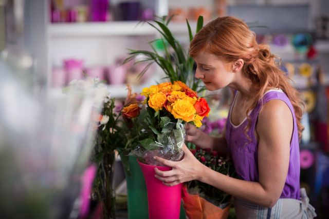Woman florist arranging a vibrant flower bouquet in a flower shop. Ideal for use in articles about floristry, small businesses, retail, gardening, and professional occupations. Can be used in promotional materials for flower shops, gardening tools, and floral arrangement courses.
