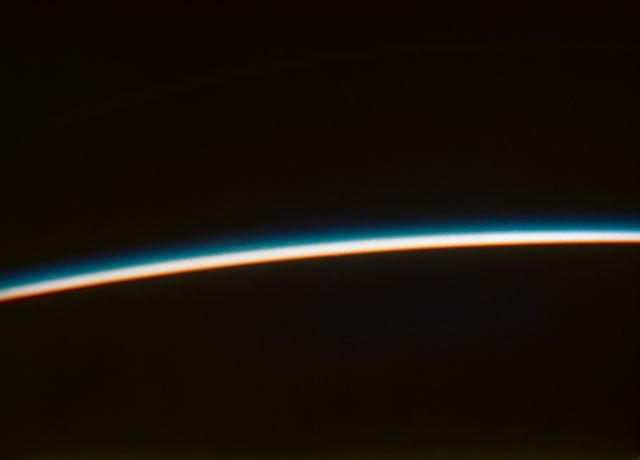 Orbital sunset seen from space by astronaut John H. Glenn Jr. during his historic Friendship 7 mission in the Mercury-Atlas 6 spaceflight in 1962. Horizon shows Earth's atmosphere transitioning from twilight into night. Suitable for use in articles, documentaries, and educational materials about space exploration, significant moments in NASA history, and scientific research on Earth's atmosphere.