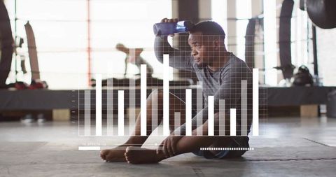 Male Athlete Resting With Water Bottle in Modern Gym Environment