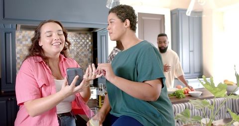 Friends Gathering in Kitchen Sharing Smartphone Fun